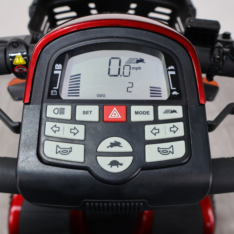 Close-up of a black and red electric scooter dashboard display with multiple control buttons, including directional arrows, mode, set, and hazard lights.