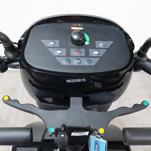 Close-up of a black electric scooter or moped dashboard with a central control panel, handlebar grips, and a small white sticker reading 98205615 on the front.