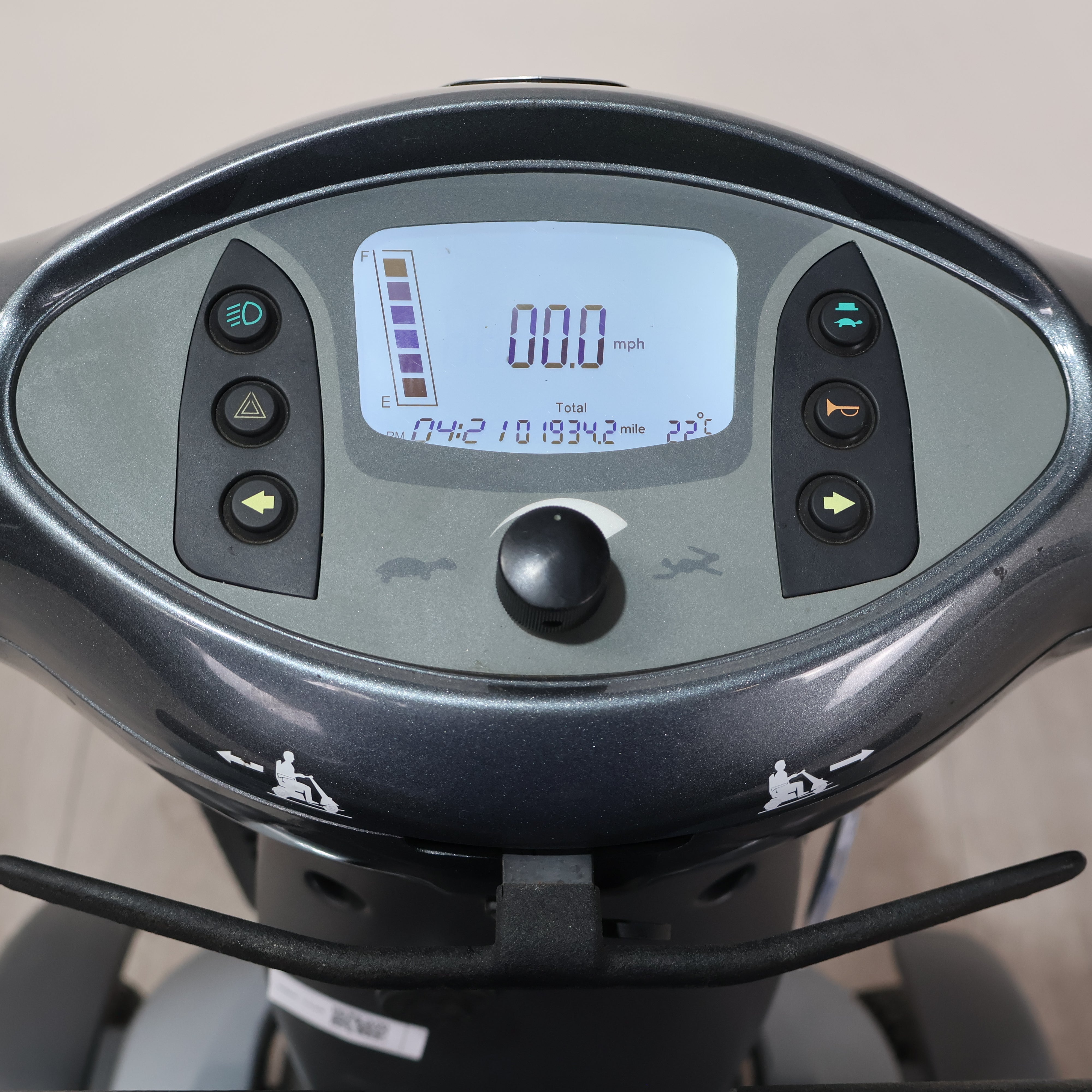 Close-up of a dark gray electric scooter dashboard with a digital display screen, control buttons, and handlebar components.