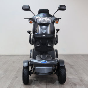 A gray and black IHQ electric three-wheel mobility scooter photographed from the front, set against a plain light gray wall and gray wood-look floor.