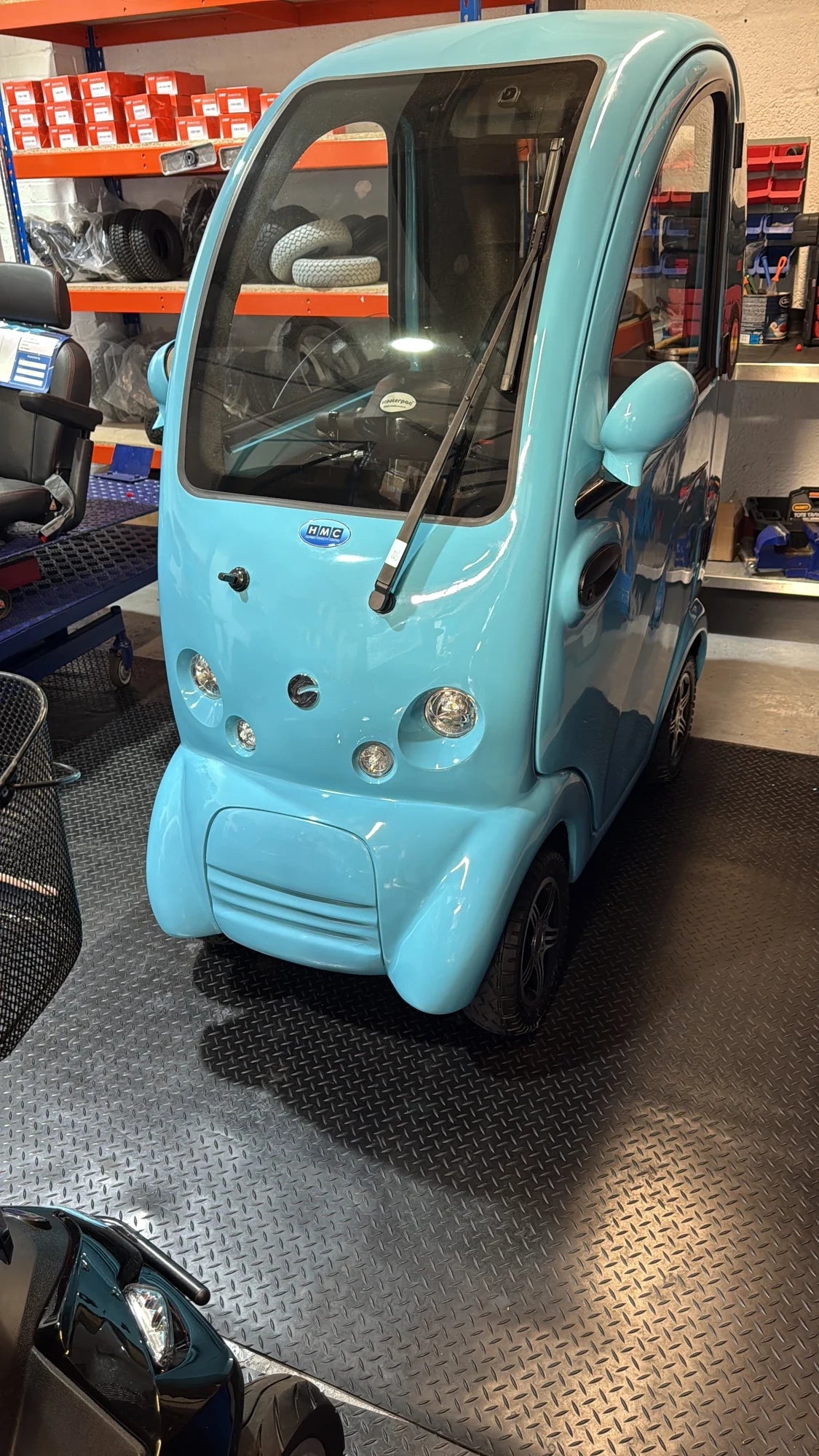 A blue Scooterpac Cabin Car enclosed mobility vehicle inside the Humber Mobility Centre workshop in Hull